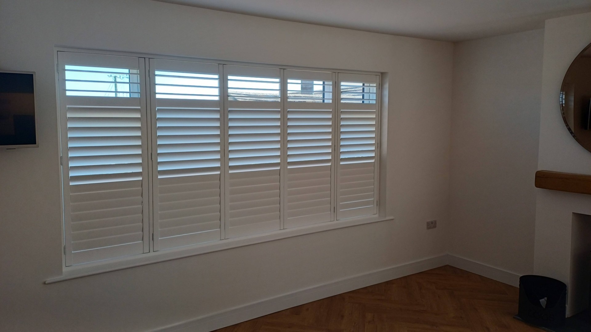 White five-panel plantation shutters in a lounge by Shires Shutters