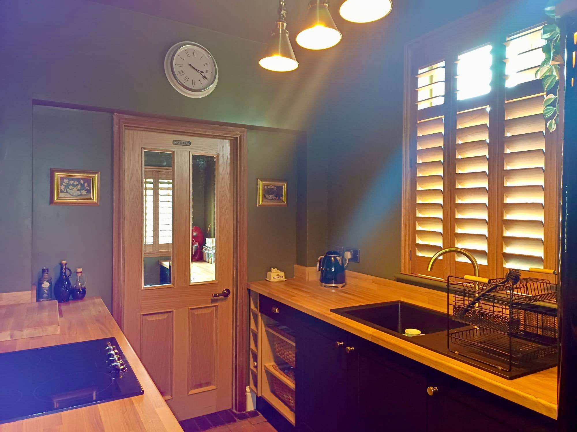 Stained hardwood plantation shutters with visible wood grain fitted to a kitchen window by Shires Shutters